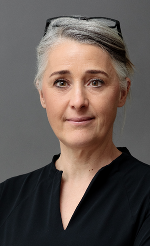 Nahaufnahme einer Person mit zurückgebundenem Haar. Blick in die Kamera, positive Ausstrahlung.